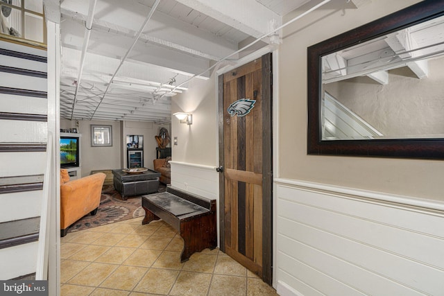 corridor featuring beam ceiling, light tile patterned floors, and wooden ceiling