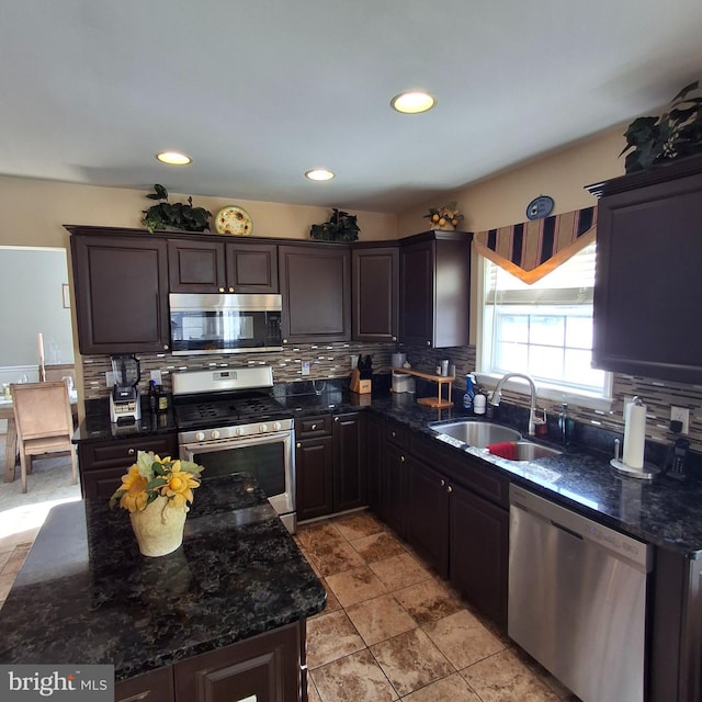 kitchen with stainless steel appliances, sink, backsplash, and dark stone counters