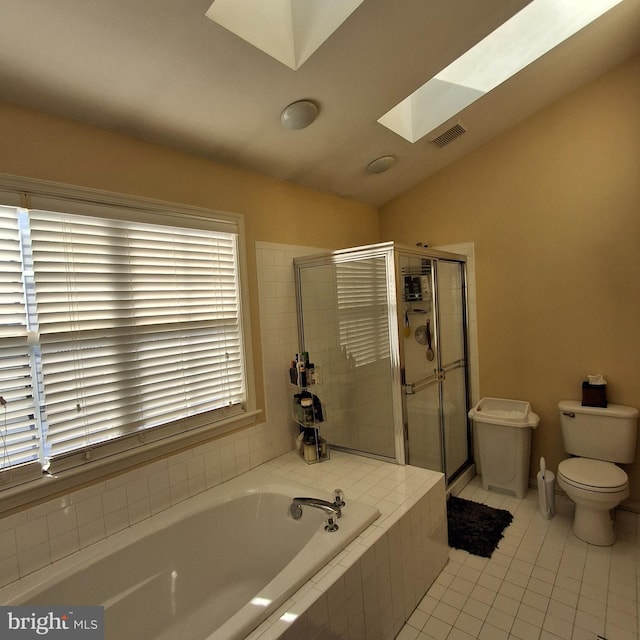 bathroom featuring toilet, lofted ceiling with skylight, separate shower and tub, and tile patterned flooring