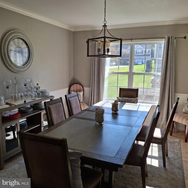 dining room with ornamental molding, hardwood / wood-style floors, and a notable chandelier