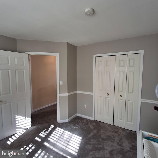 unfurnished bedroom with dark colored carpet and a closet