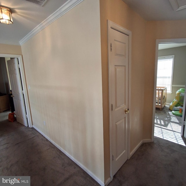 corridor with ornamental molding and dark colored carpet