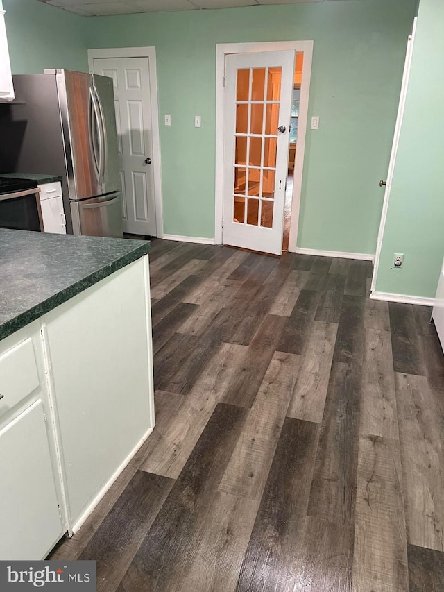 kitchen with dark hardwood / wood-style floors, white cabinetry, and stainless steel refrigerator