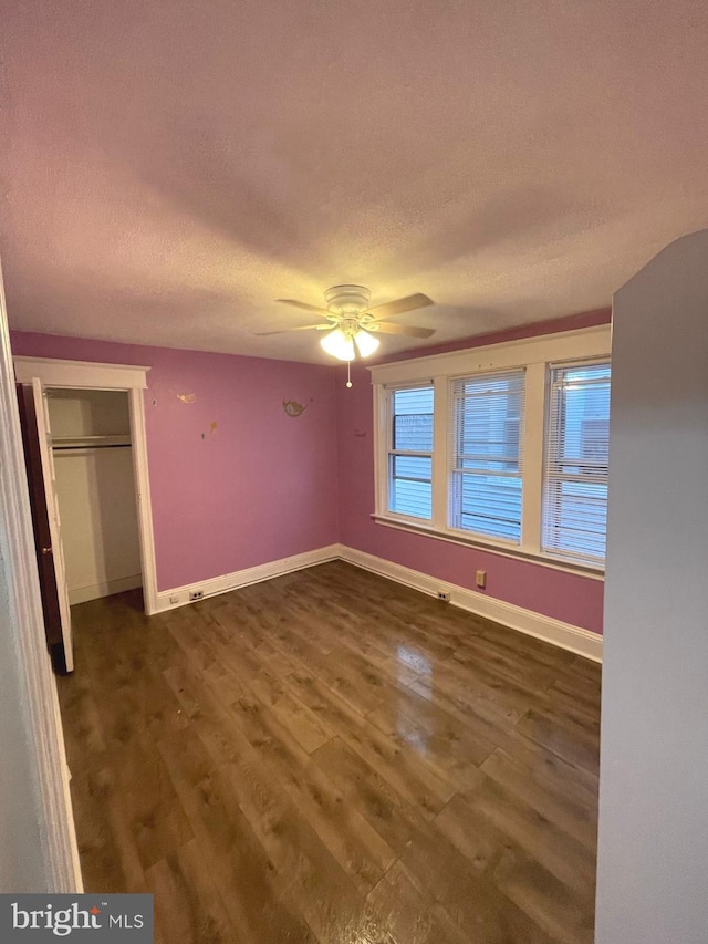 unfurnished bedroom with a textured ceiling, ceiling fan, a closet, and dark hardwood / wood-style floors