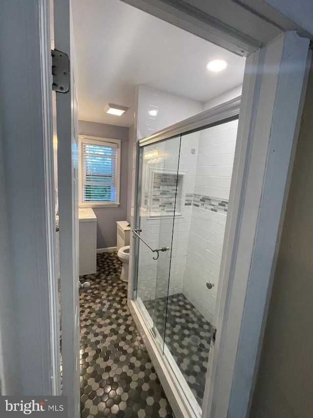 bathroom with walk in shower, vanity, and toilet