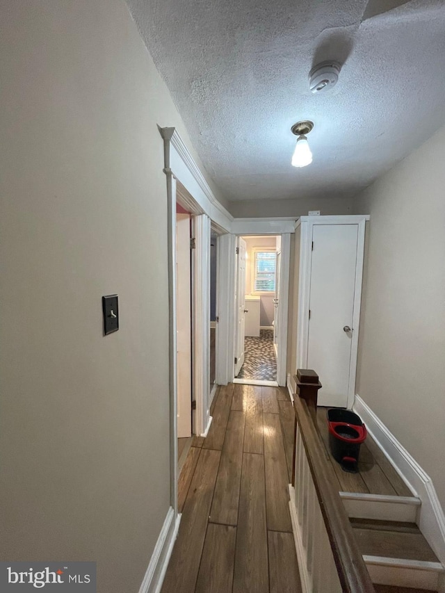 corridor with wood-type flooring and a textured ceiling