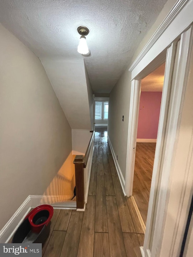 corridor featuring a textured ceiling and dark wood-type flooring