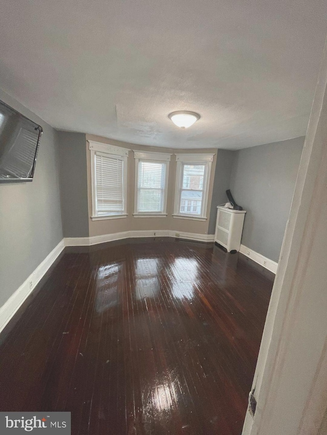 bonus room with a textured ceiling and dark wood-type flooring