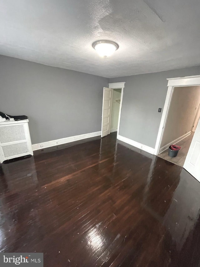 interior space featuring a textured ceiling and dark hardwood / wood-style floors