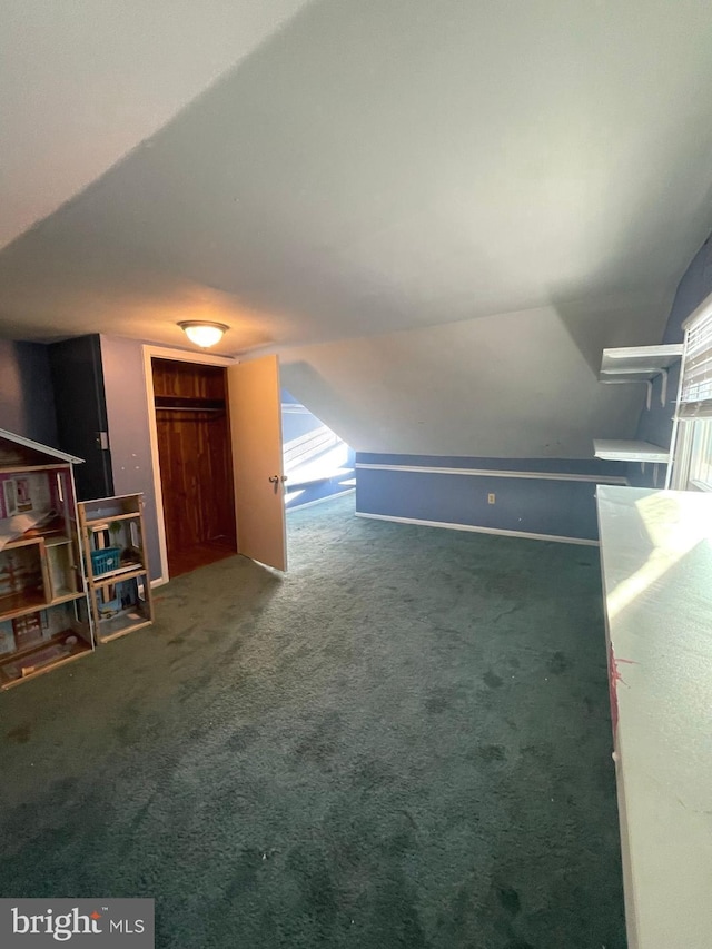 bonus room with dark carpet and lofted ceiling