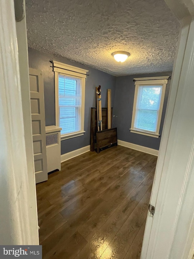 unfurnished bedroom with a textured ceiling and dark hardwood / wood-style floors