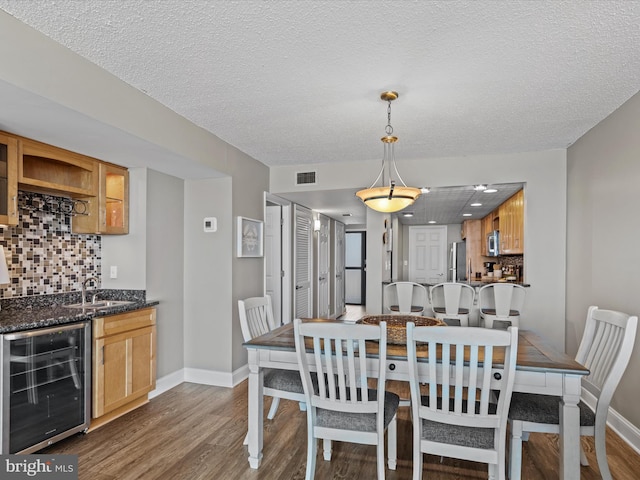 701 S Edgewater House Rd Unit 701S, Bethany Beach, DE 19930 - dining area featuring wine cooler, dark wood-type flooring, wet bar, and a textured ceiling