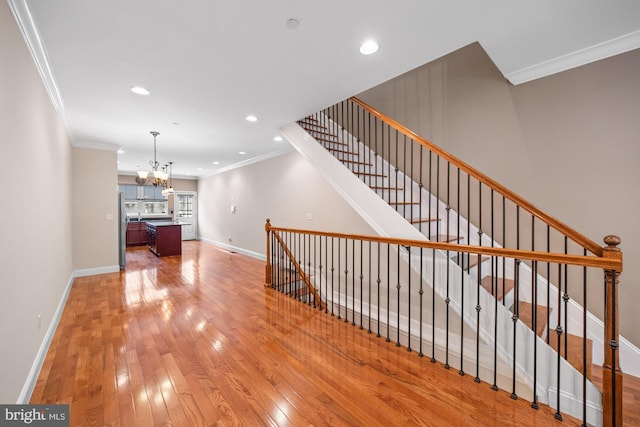 interior space featuring a notable chandelier, light wood-type flooring, and ornamental molding