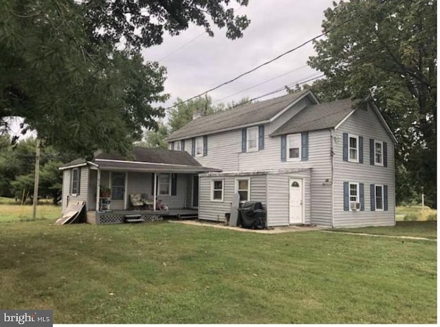 rear view of house with a lawn and a porch