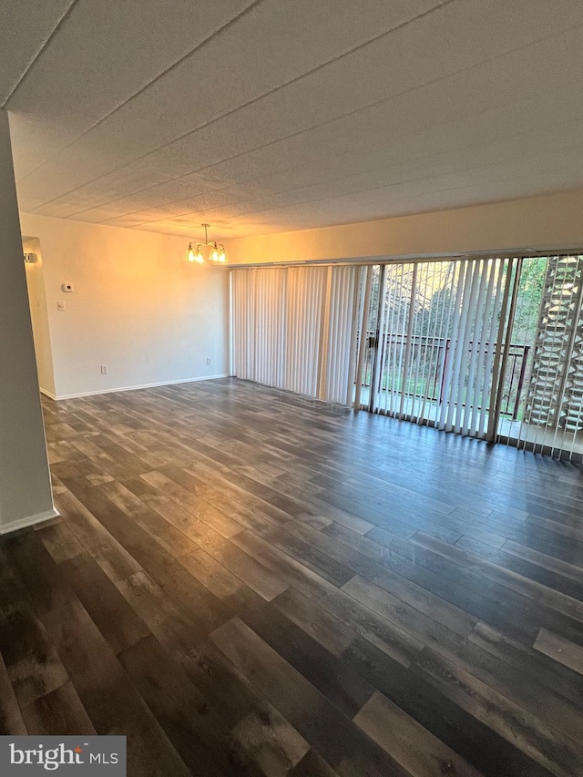 unfurnished room featuring dark hardwood / wood-style flooring and an inviting chandelier