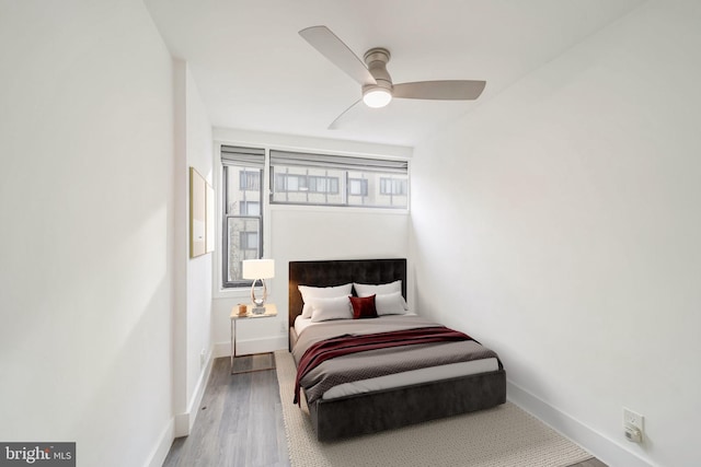 bedroom with ceiling fan, multiple windows, and hardwood / wood-style flooring