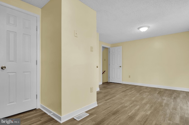 spare room featuring a textured ceiling and light hardwood / wood-style flooring