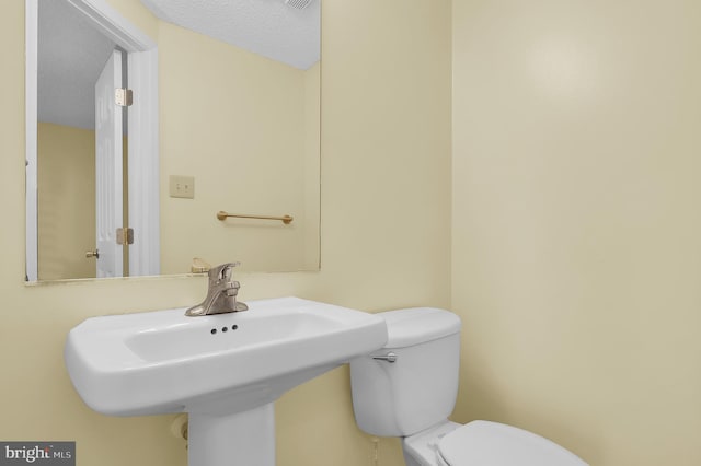 bathroom with sink, toilet, and a textured ceiling