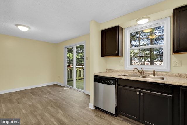 kitchen featuring dark brown cabinetry, sink, light hardwood / wood-style flooring, stainless steel dishwasher, and a textured ceiling