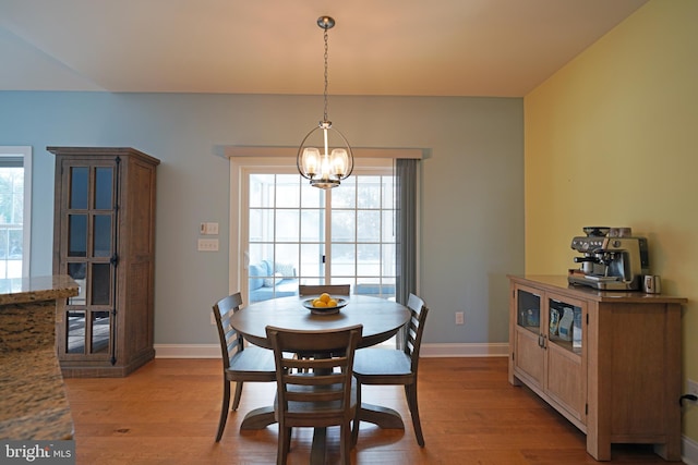 dining space with light hardwood / wood-style flooring and a notable chandelier