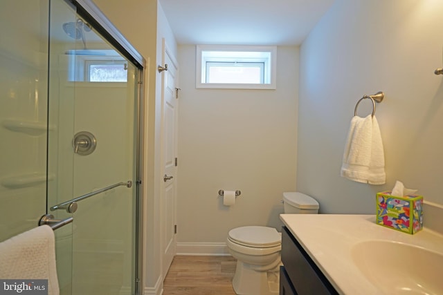 bathroom with hardwood / wood-style floors, vanity, toilet, and a shower with shower door