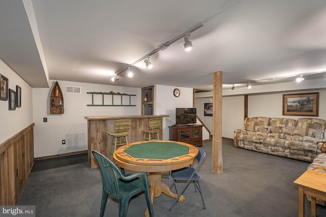 dining room with dark colored carpet, track lighting, and bar area