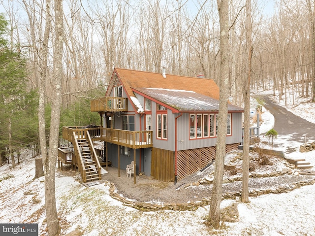 snow covered back of property featuring a deck