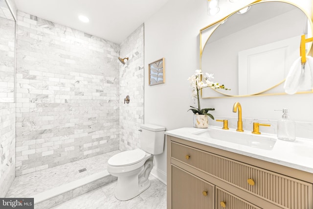 bathroom featuring a tile shower, vanity, and toilet