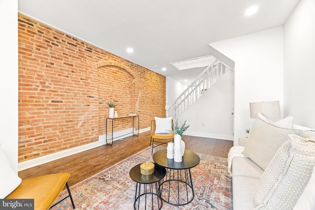 living room featuring hardwood / wood-style flooring and brick wall