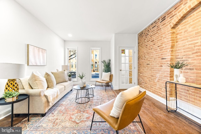 living room featuring hardwood / wood-style flooring and brick wall