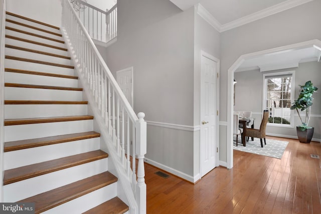 stairway featuring ornamental molding, wood-type flooring, visible vents, and baseboards