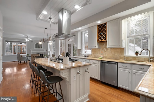 kitchen with a fireplace, island exhaust hood, decorative backsplash, appliances with stainless steel finishes, and a sink