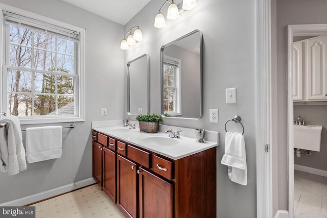 bathroom featuring tile patterned floors, a sink, baseboards, and double vanity