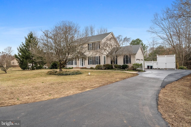 view of front of house featuring driveway, a front lawn, and fence