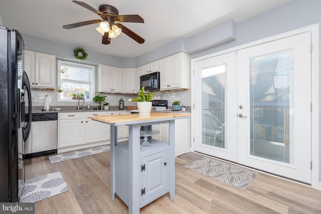 kitchen with wood counters, light hardwood / wood-style floors, white cabinetry, and black appliances