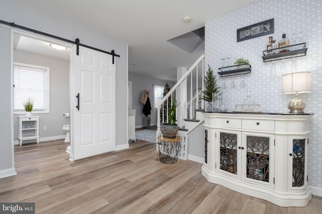 foyer featuring a barn door, light hardwood / wood-style floors, and tile walls