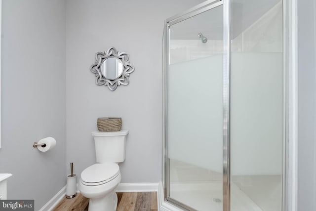 bathroom with hardwood / wood-style floors, toilet, and a shower with shower door