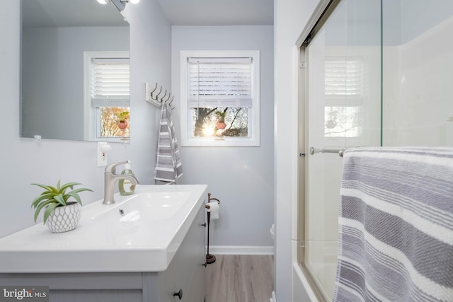 bathroom with hardwood / wood-style floors, vanity, and combined bath / shower with glass door