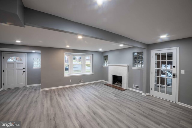 unfurnished living room featuring light hardwood / wood-style floors and a brick fireplace