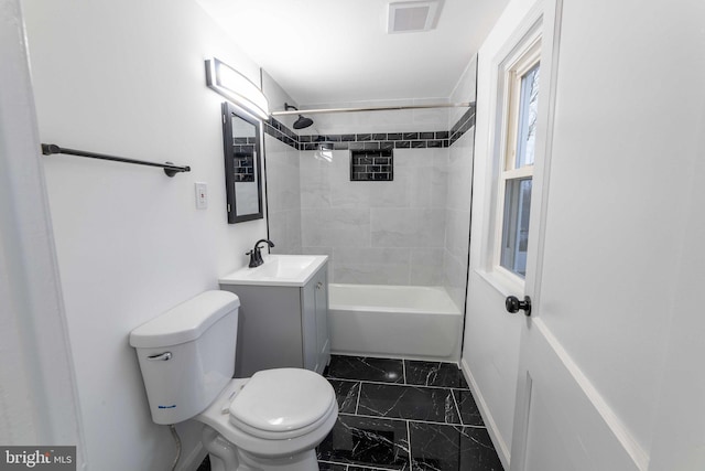 full bathroom featuring tiled shower / bath, vanity, and toilet