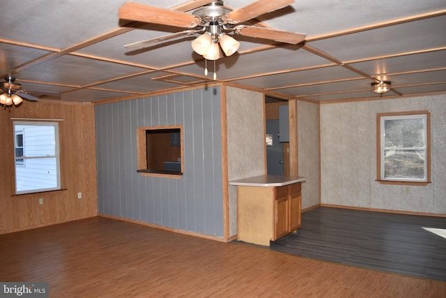 unfurnished living room featuring ceiling fan, wooden walls, and dark hardwood / wood-style floors