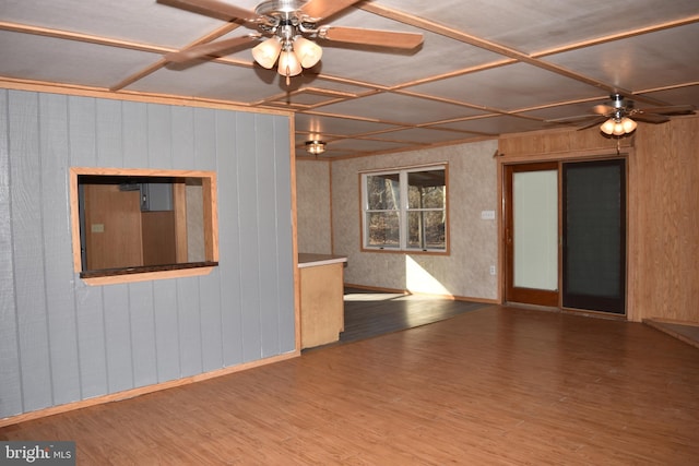 unfurnished room featuring ceiling fan, wood-type flooring, and wood walls