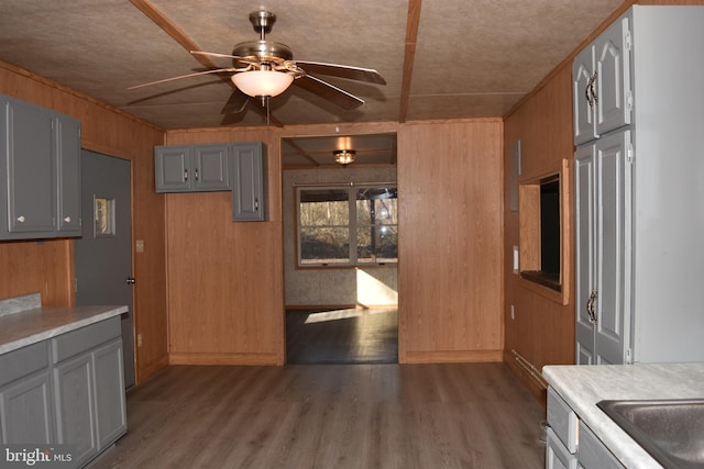 kitchen with gray cabinetry, wood walls, ceiling fan, and wood-type flooring