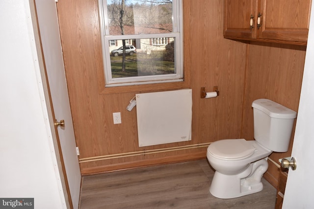 bathroom with radiator heating unit, hardwood / wood-style flooring, toilet, and wood walls