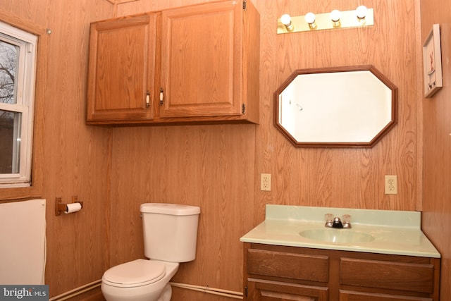 bathroom featuring vanity, toilet, and wooden walls