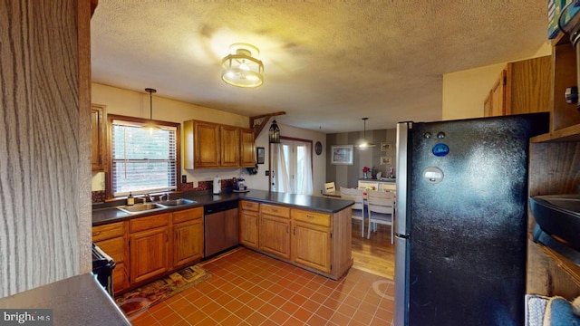 kitchen with sink, hanging light fixtures, a textured ceiling, kitchen peninsula, and stainless steel appliances