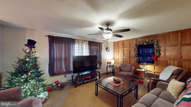 living room with ceiling fan, carpet floors, a baseboard radiator, and wood walls