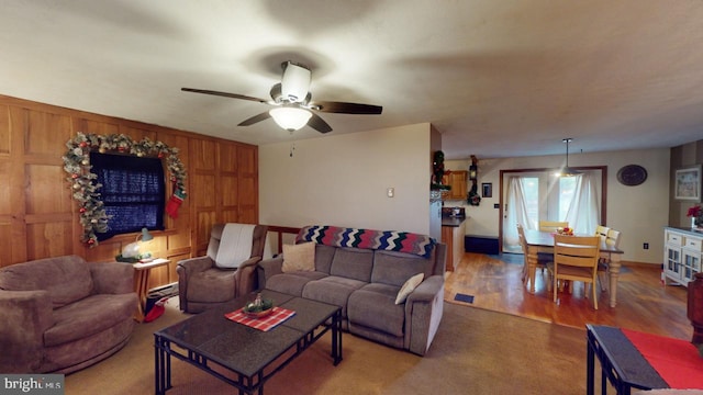 living room featuring ceiling fan, wood walls, and hardwood / wood-style flooring