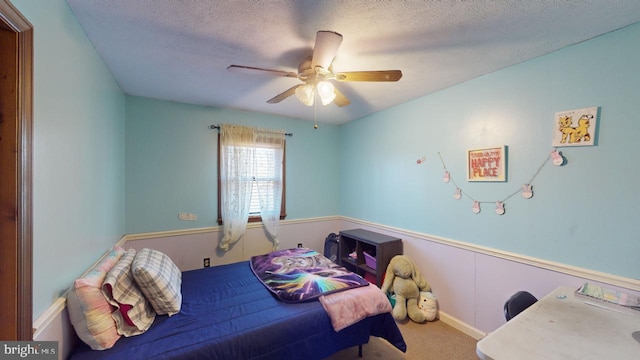 bedroom with ceiling fan, carpet floors, and a textured ceiling