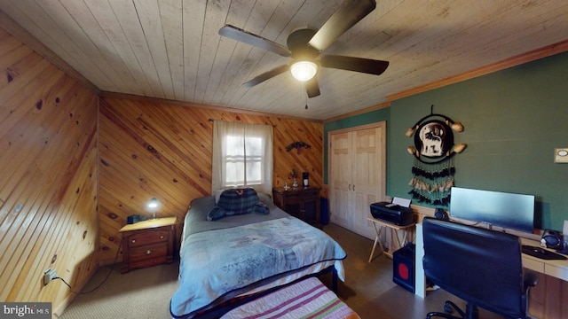 bedroom featuring ceiling fan, wood ceiling, wooden walls, and a closet